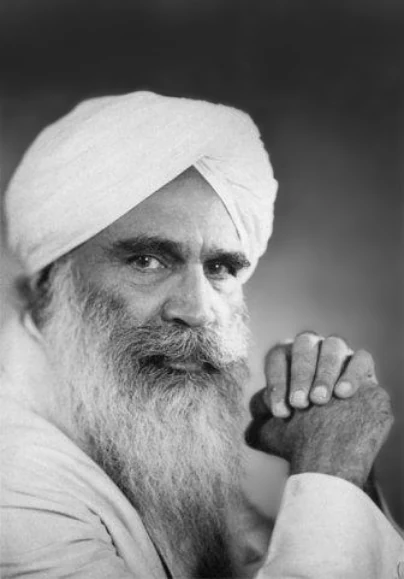 Portrait of Sant Kirpal Singh in a white turban, seated with his hands clasped
